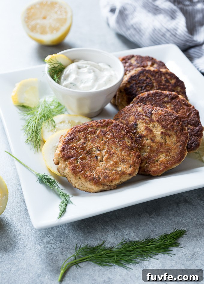 Salmon patties on a platter with lemon dill sauce