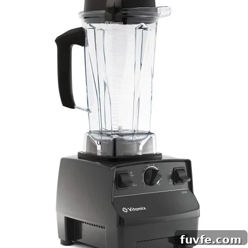 A black Vitamix blender with a clear plastic pitcher, black lid, and handle, featuring control dials and switches on the front of the base.