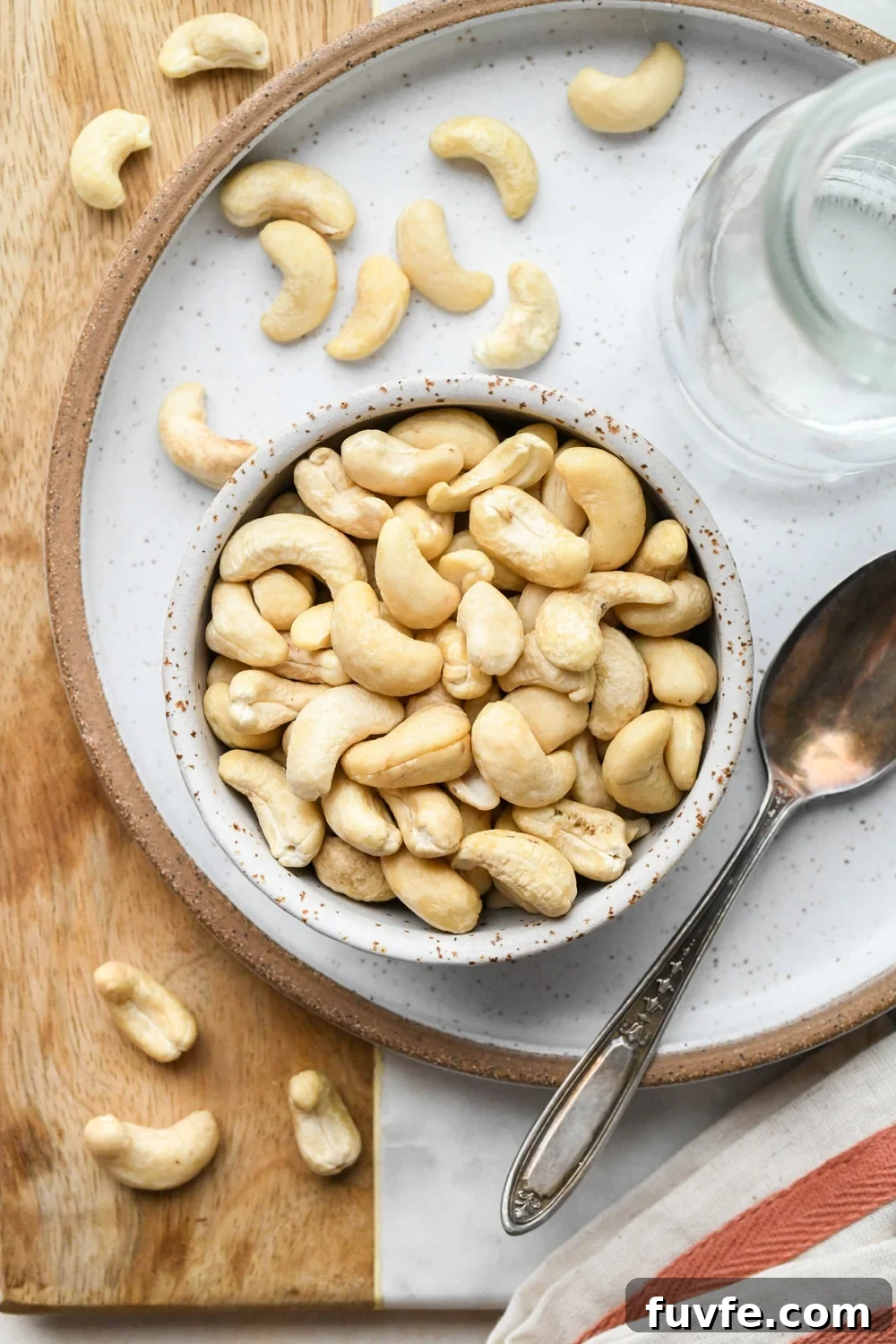 Ingredients for cashew cream in ceramics - raw cashews in a small bowl, and water in a glass jar.