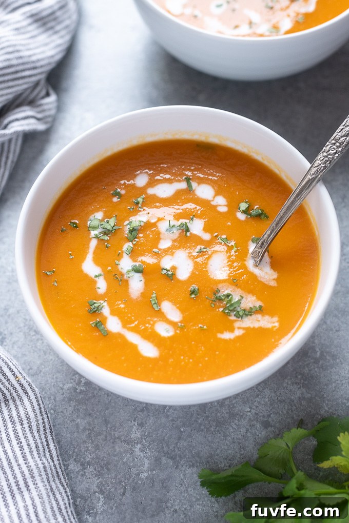 Silky Carrot and Ginger Soup Recipe 7 Carrot soup in a white bowl with spoon digging in