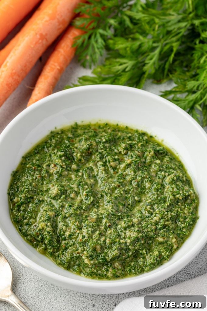 Carrot top pesto sauce in a bowl with carrots alongside