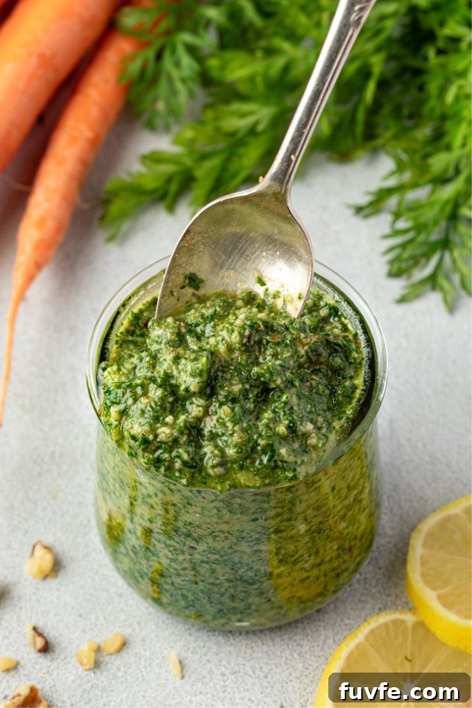 Fresh Carrot-Top Pesto Recipe with Lemon and Parmesan 7 Spoon digging into a jar of carrot top pesto