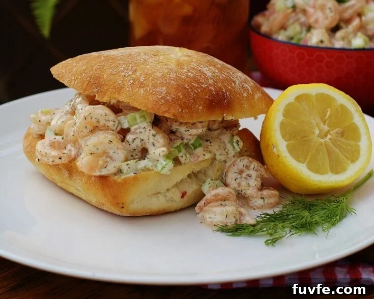 A completed Southern Shrimp Salad Roll on a plate with half a lemon and some dill.