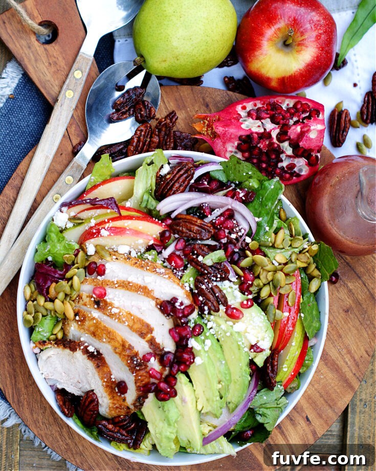 An overhead photo of apple pear pomegranate salad with chicken and avocado