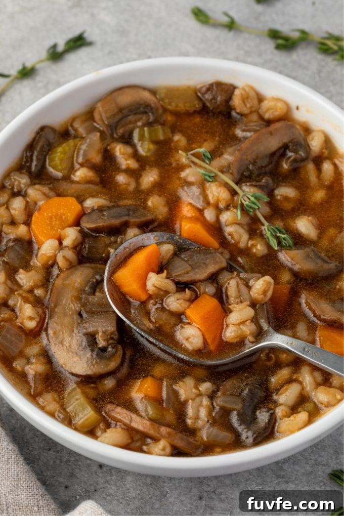 Bowl of vegetarian mushroom barley soup with spoon digging in