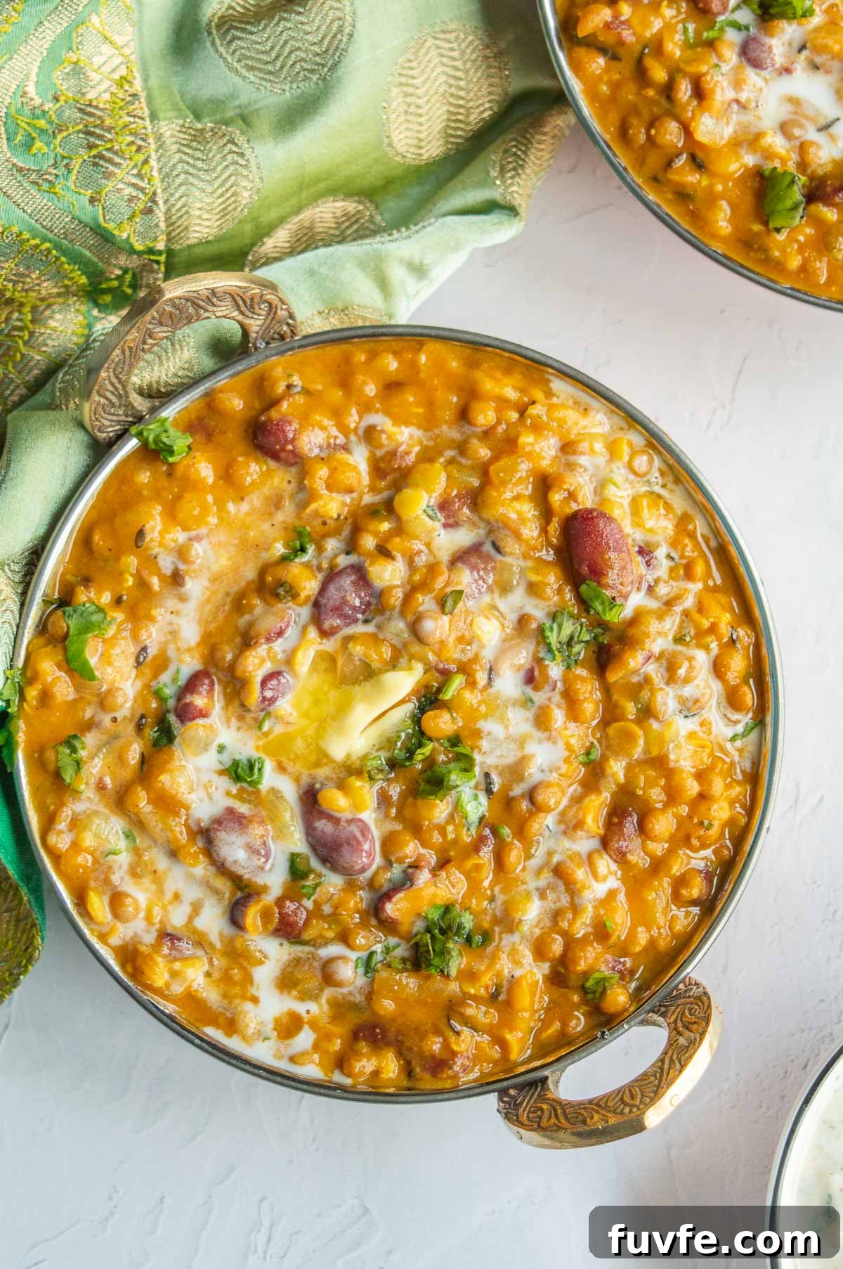 Copper bowls filled with a thick lentil and kidney bean mixture in orange-brown sauce.