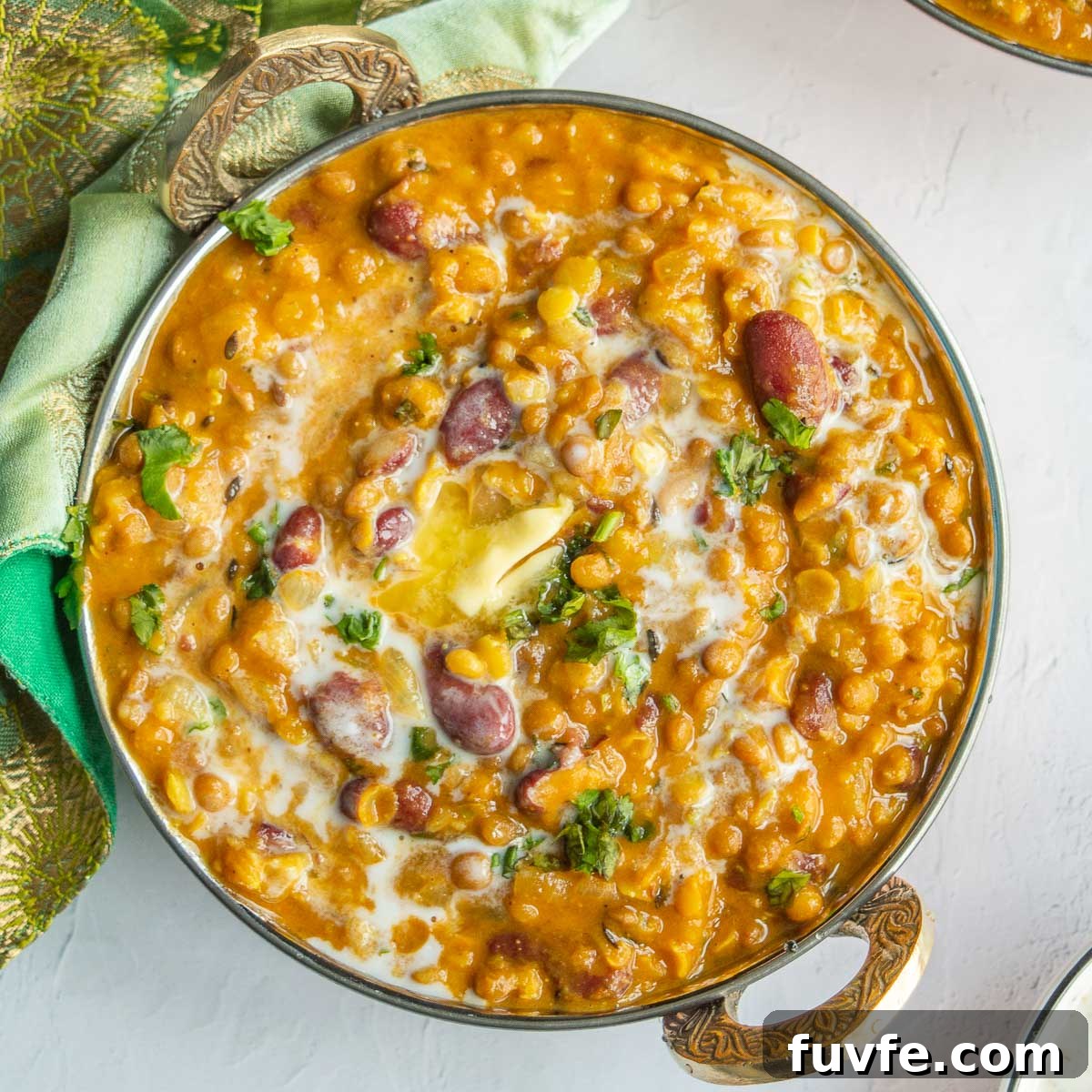 A large copper bowl with lentils and kidneys beans in a brown sauce.