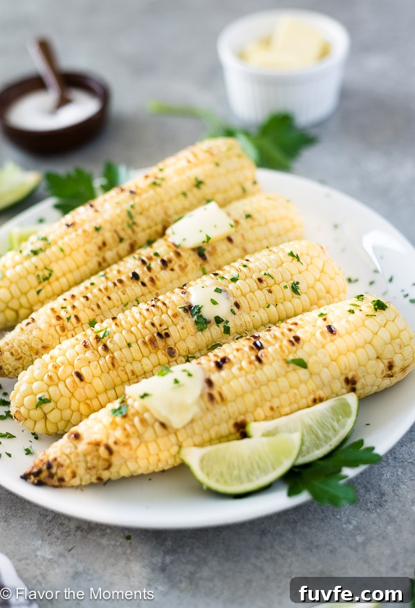 close up front view of grilled corn on the cob with butter and lime wedges