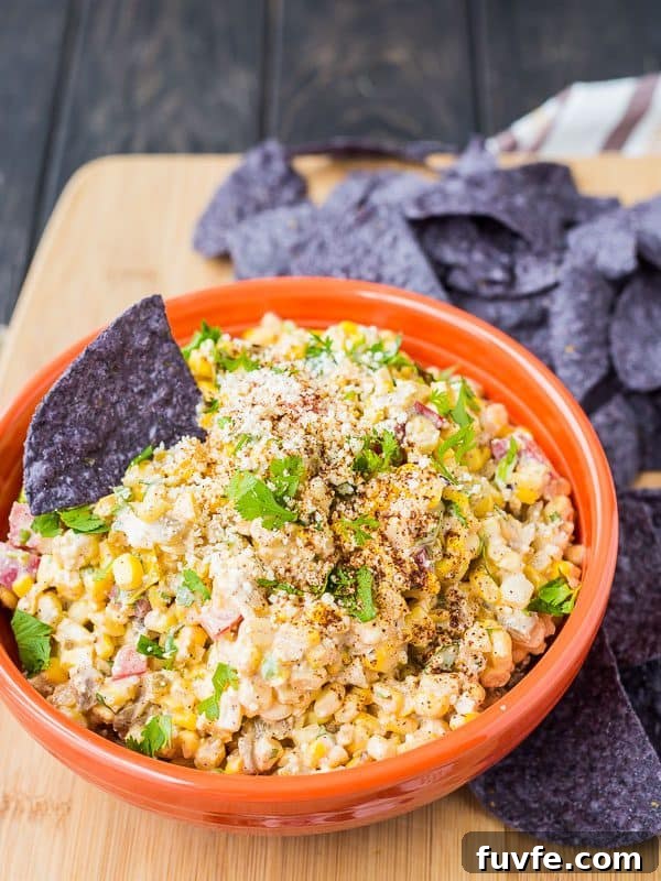 Mexican corn dip and a blue tortilla chip in an orange dip.