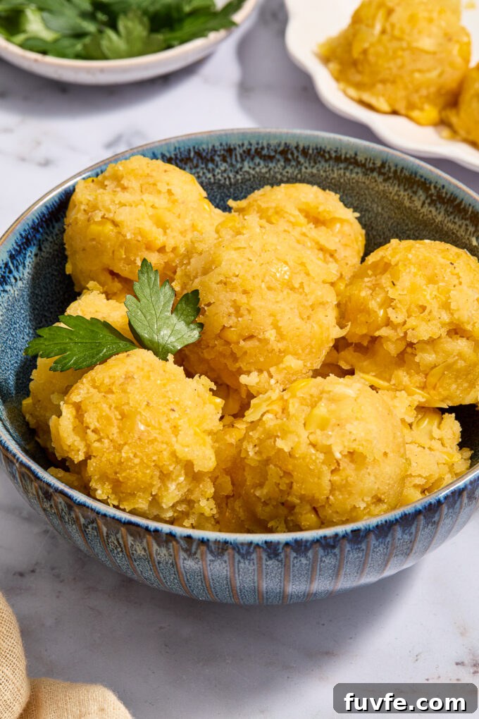 Scoops of Mexican sweet corn cake in a bowl with cilantro sprig.