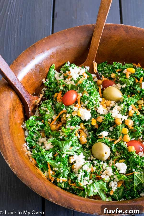 A wooden bowl full of roasted corn and chickpea salad with two wooden serving spoons.