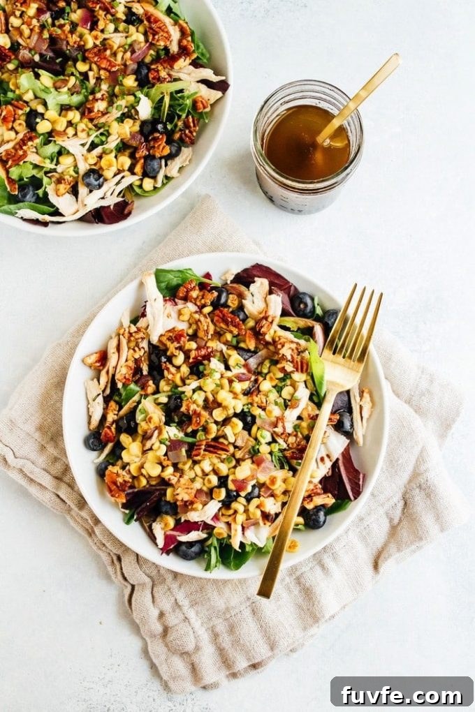Blueberry corn chicken salad in a white bowl with a fork.