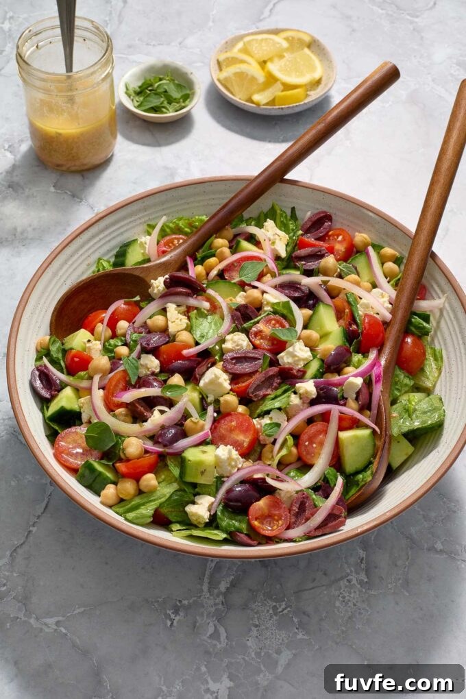 Mediterranean chopped salad in a bowl with salad servers.