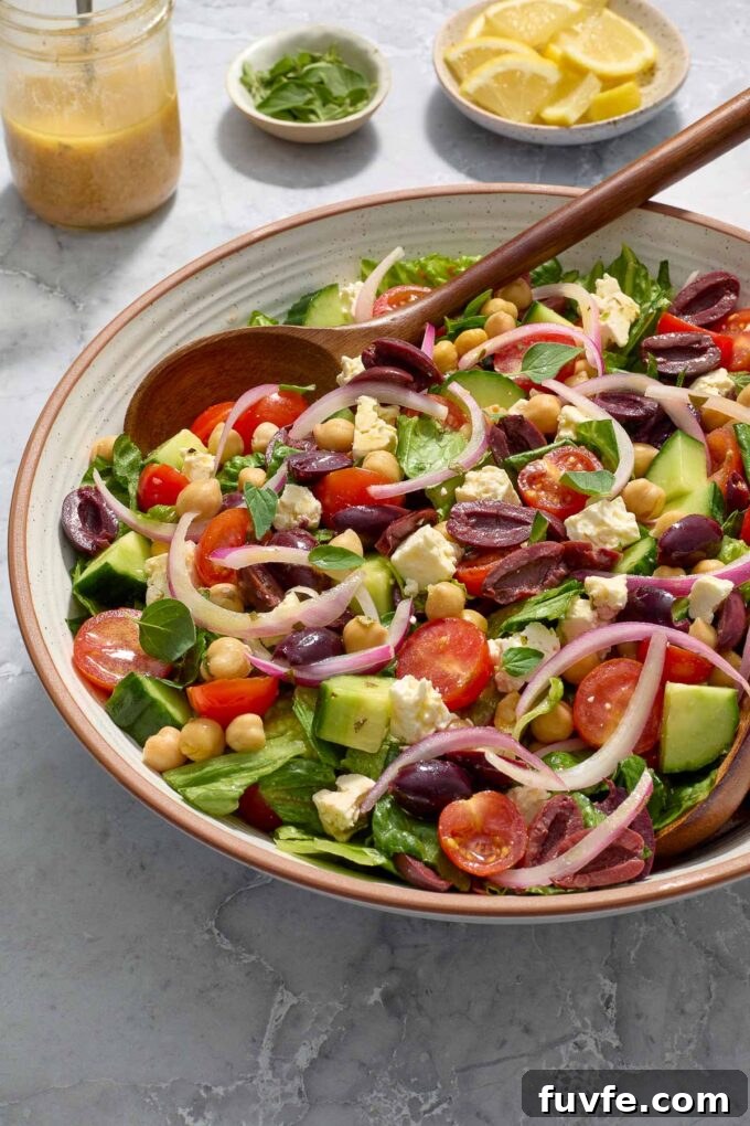 Mediterranean salad in a bowl with salad servers digging in.