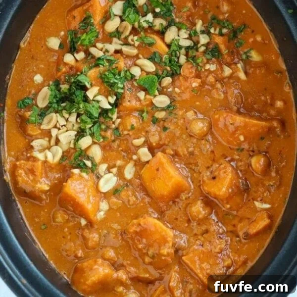 Sweet potato and peanut butter vegan stew in a slow cooker, garnished with peanuts and parsley.