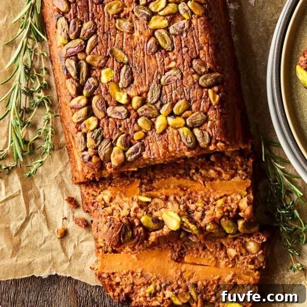 A nut roast on baking paper, with a couple of slices laying down to reveal the inside filling.