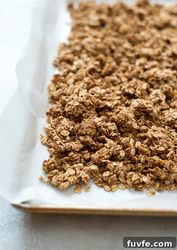 Almond butter granola broken into clusters on baking sheet.