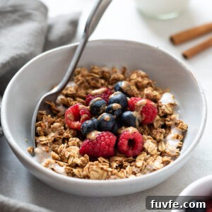Crunchy Almond Butter Granola Recipe 9 Almond butter granola in a bowl with berries and almond butter drizzle.