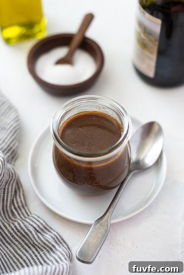 overhead shot of balsamic vinaigrette dressing in a jar with a spoon alongside