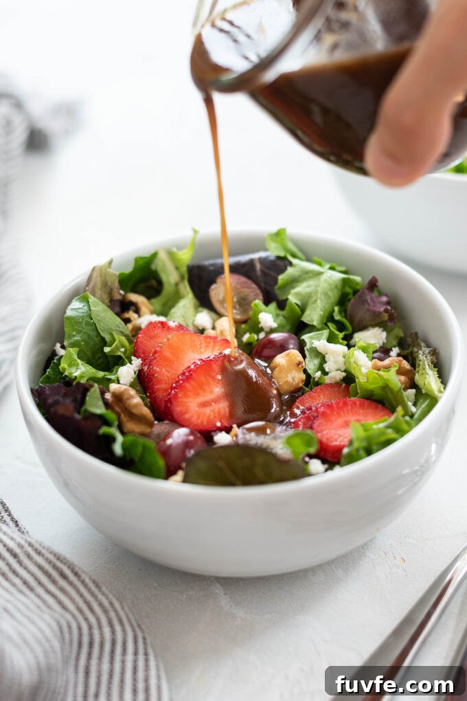 Strawberry Feta Spinach Salad with Balsamic Glaze 7 Dressing pouring over Strawberry Summer Salad.