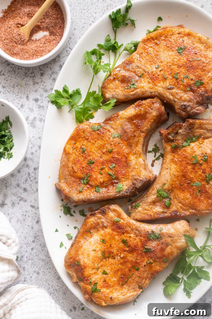 Juicy Oven-Baked Pork Chops with Garlic-Herb Crust 10 Easy baked pork chops on a platter with chopped parsley.