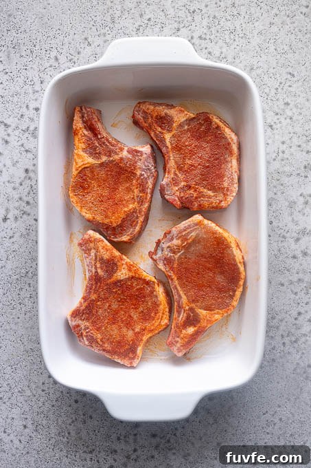 Juicy Oven-Baked Pork Chops with Garlic-Herb Crust 7 Seasoned pork chops in baking dish.
