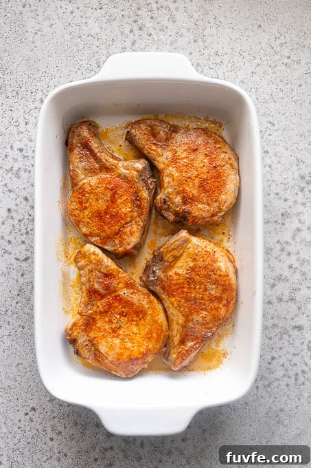 Juicy Oven-Baked Pork Chops with Garlic-Herb Crust 8 Baked bone-in pork chops in baking dish.