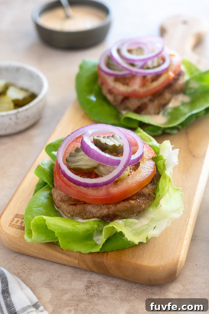 Grilled turkey burgers in lettuce wraps on a cutting board.