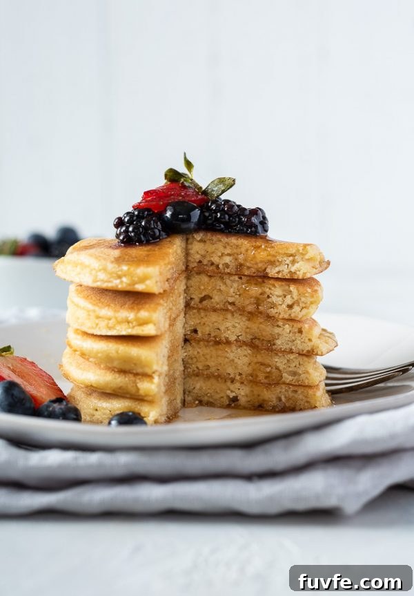 Fluffy Almond Flour Pancakes - Gluten-Free Breakfast Recipe 2 stack of almond flour pancakes with berries on top and maple syrup dripping