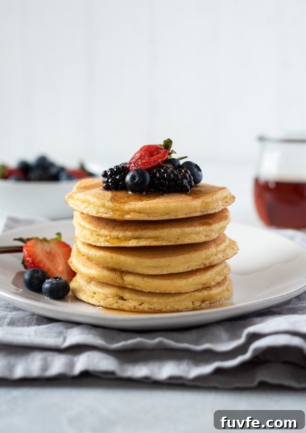 Fluffy Almond Flour Pancakes - Gluten-Free Breakfast Recipe 3 stack of grain free pancakes on a plate topped with berries