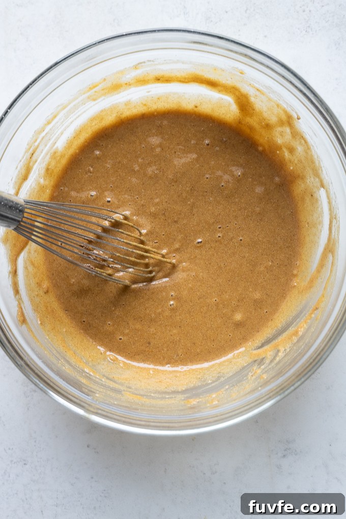 Whisked wet ingredients for pumpkin breakfast cookies in mixing bowl.