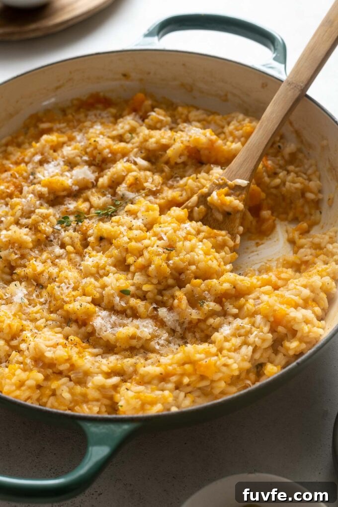 Creamy Pumpkin Risotto with Parmesan and Sage 5 Pumpkin risotto in a skillet with wooden spoon digging in.