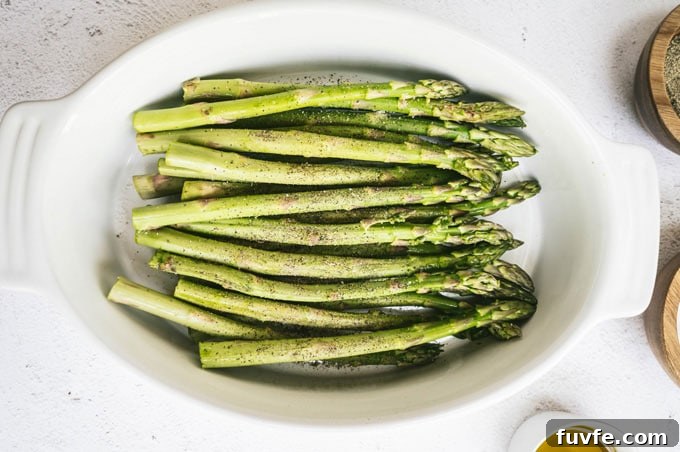 Perfect Grilled Asparagus with Lemon and Garlic 4 asparagus in a dish with salt and pepper in dishes around it