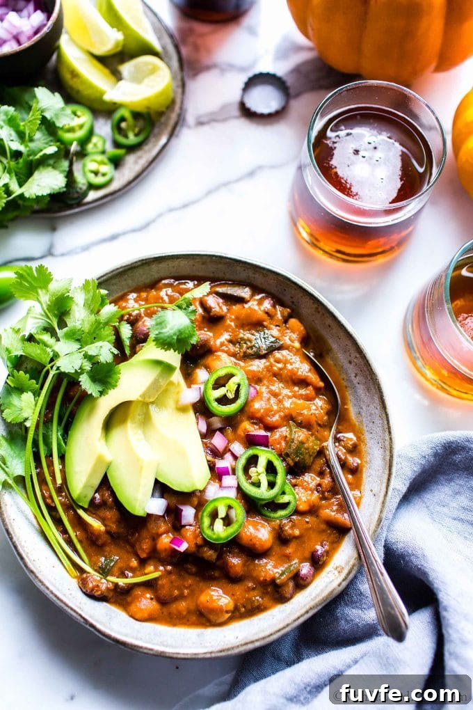 Overhead view of a bowl of kabocha squash chili topped with avocado, jalapeno slices, and cilantro.