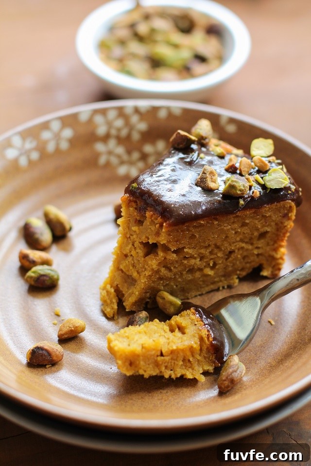 A slice of kabocha squash cake on a brown floral plate. A bite has been speared on a fork.