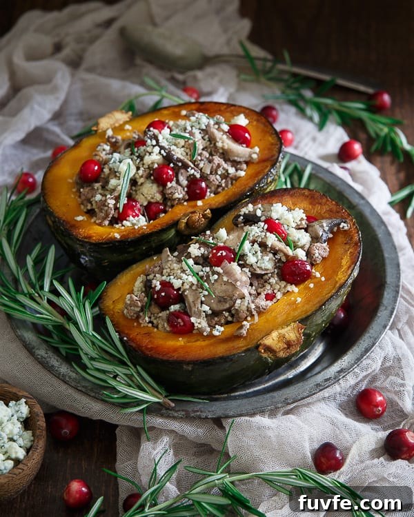 Two lamb-stuffed kabocha squash halves on a metal plate. Fresh rosemary and cranberries surround the plate.