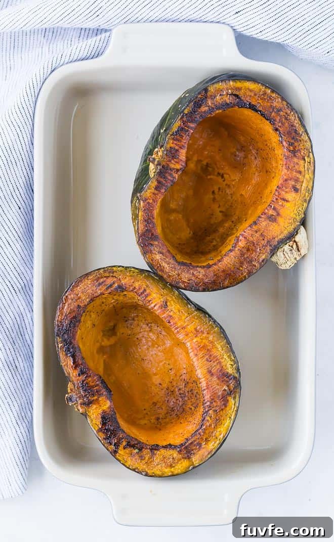 Overhead view of two roasted kabocha squash halves in a baking dish.