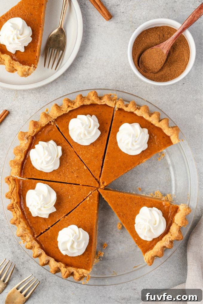 Homemade pumpkin pie in baking dish sliced with whipped cream