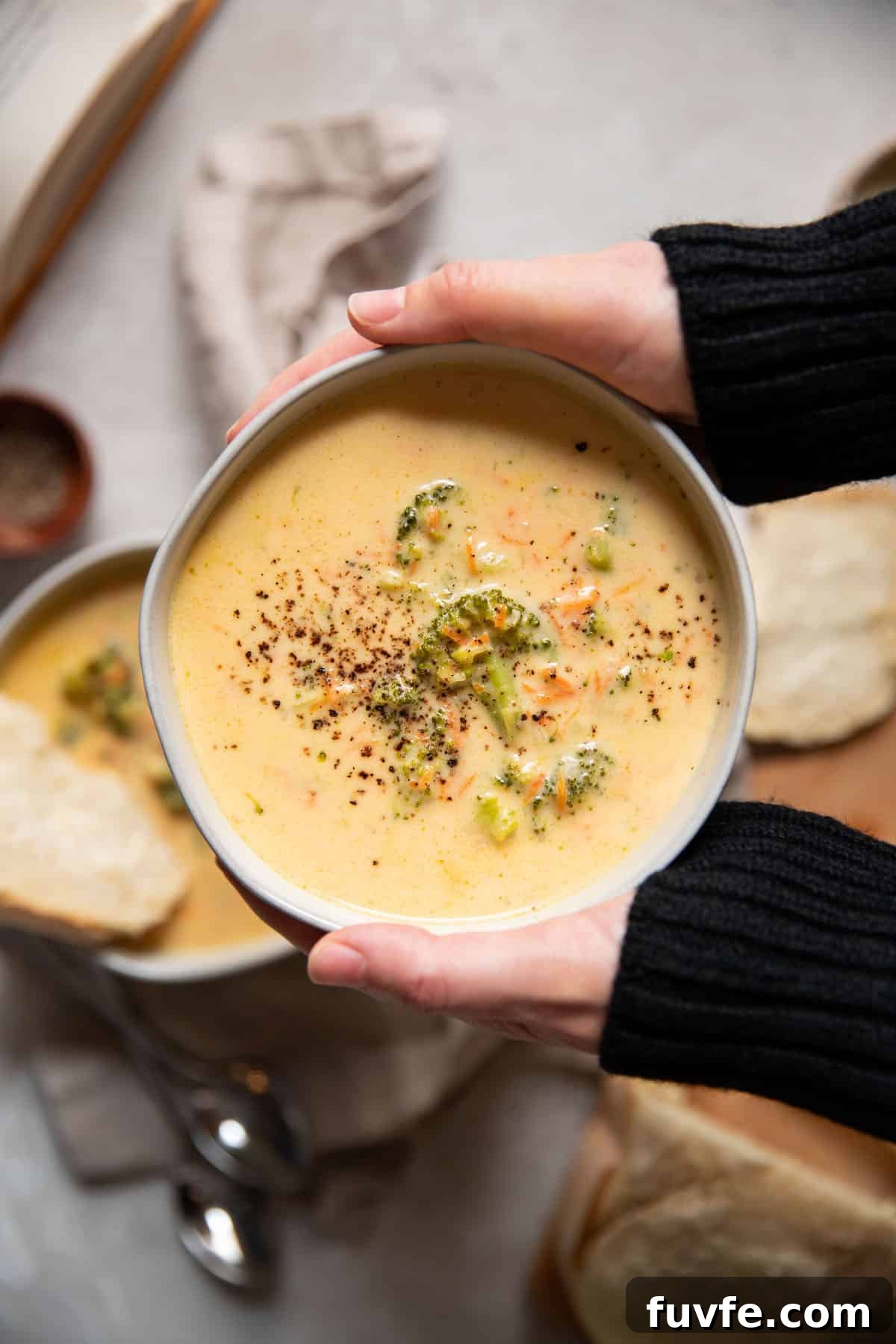 30-Minute Broccoli Cheddar Soup Recipe for Quick Comfort 3 hands holding a bowl of broccoli cheese soup