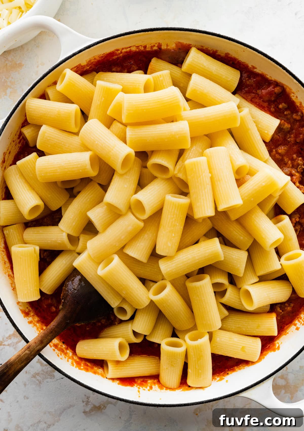 How to make classic pasta al forno step-by-step: add al dente pasta to the meat sauce and mix.