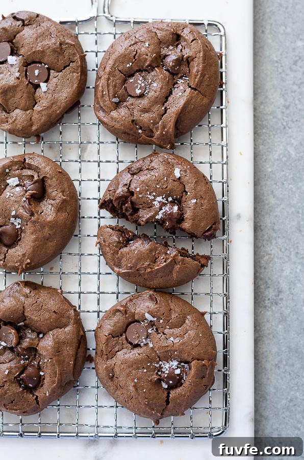 chocolate peanut butter cookies on a wire rack with close up on one split in half