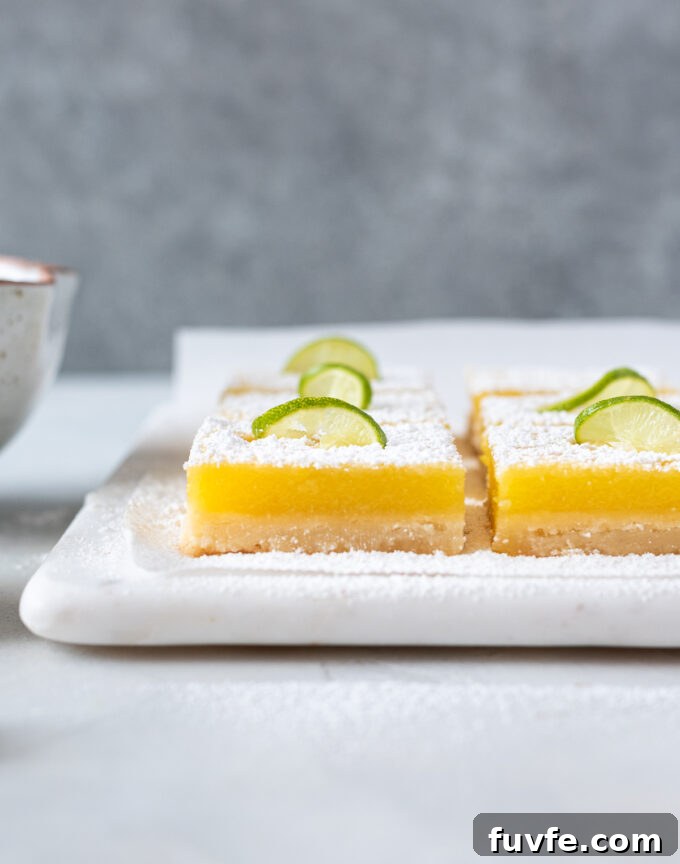 Zesty Key Lime Shortbread Bars Recipe 10 Key lime bars with powdered sugar and lime slice on top.