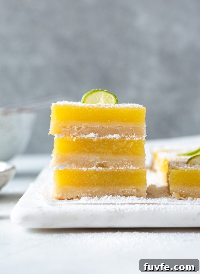 Zesty Key Lime Shortbread Bars Recipe 11 Stack of key lime shortbread bars with lime slice on top.