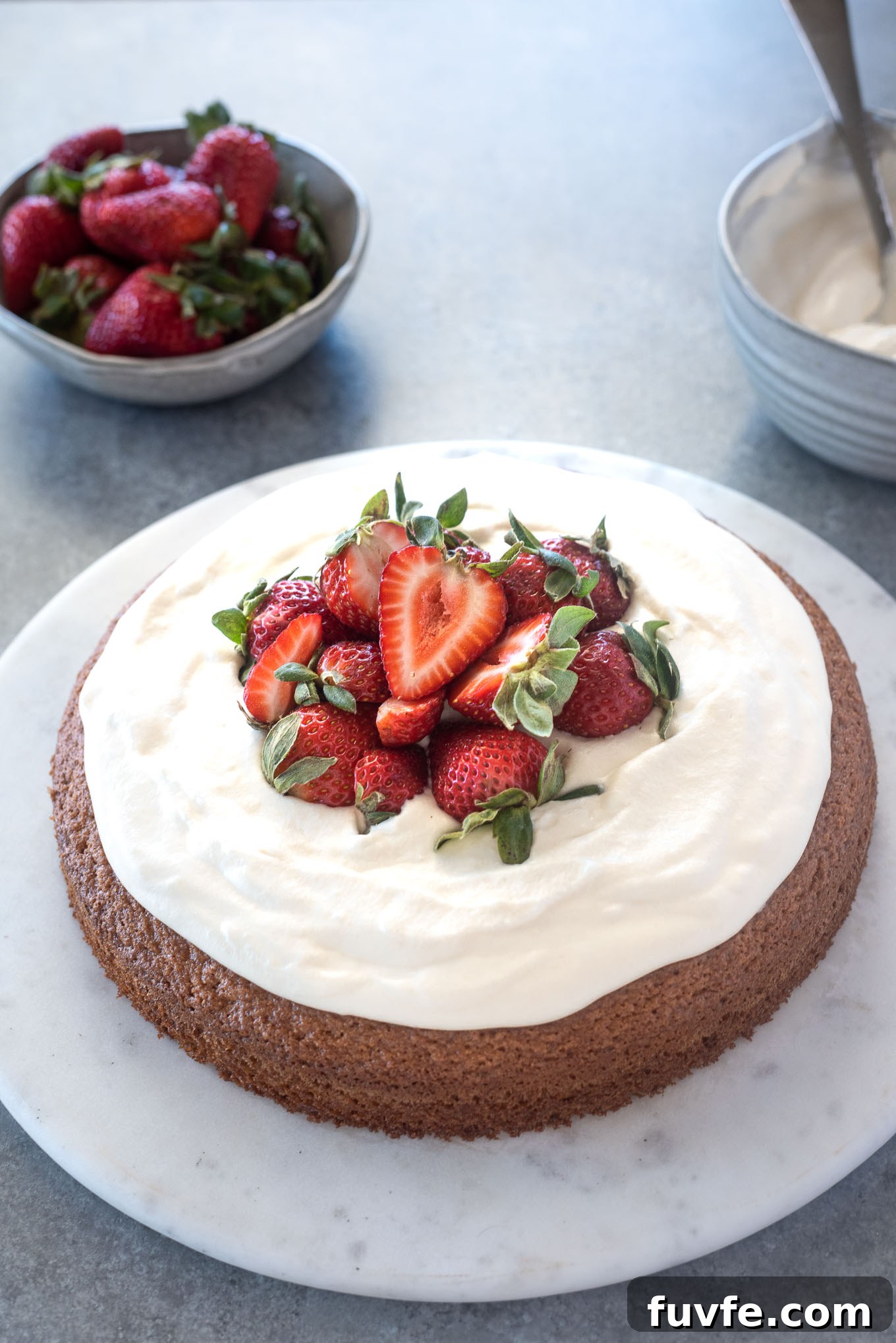 Almond flour cake topped with strawberries and whipped cream