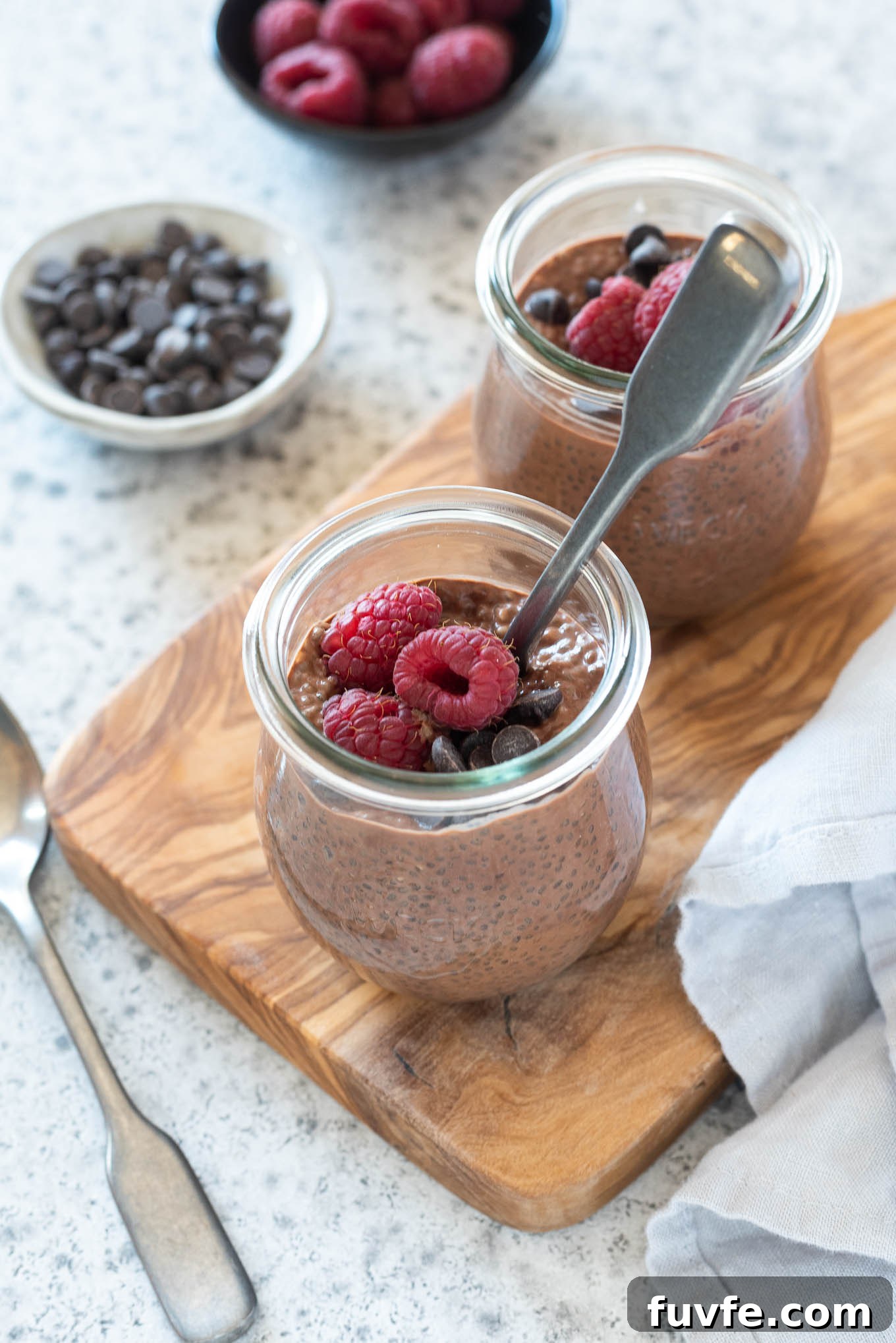 Chocolate Chia Pudding in jars with raspberries on top