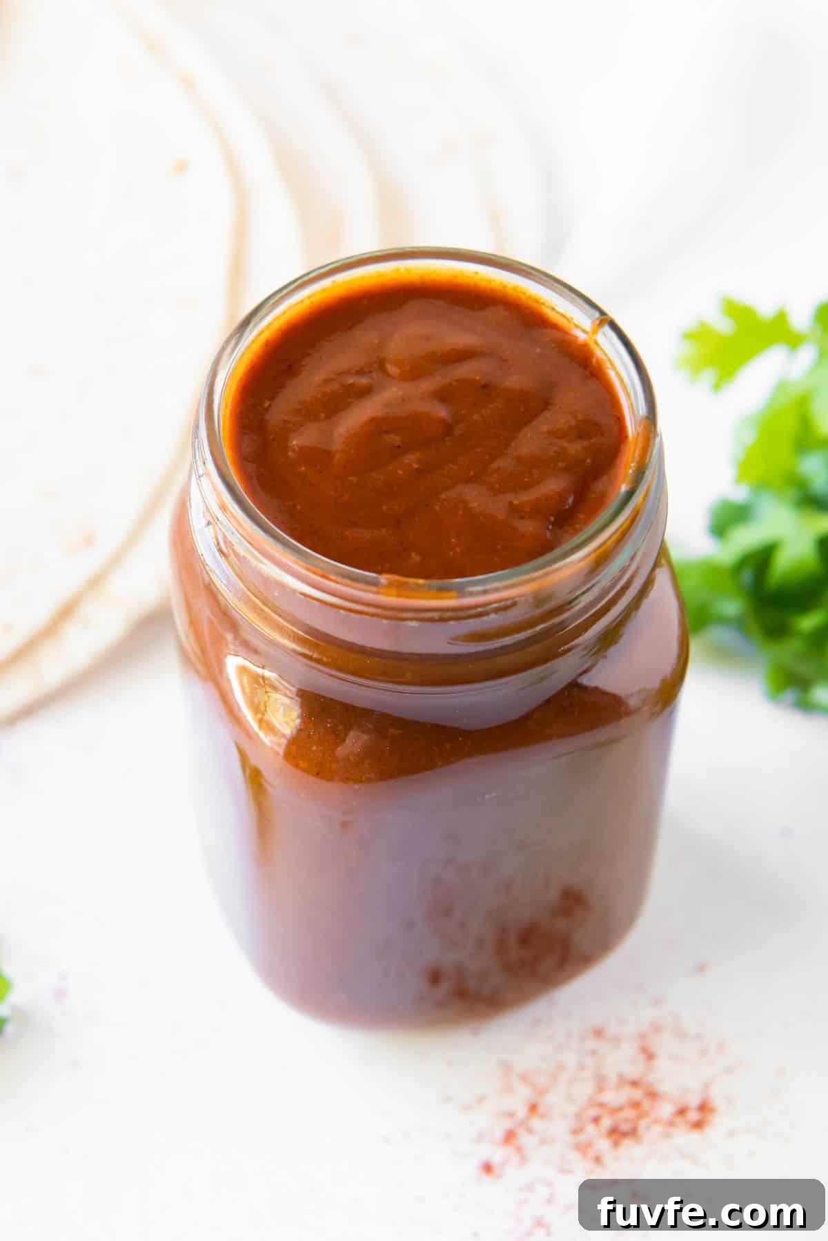 A glass jar filled with homemade enchilada sauce.
