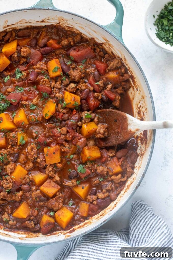 Hearty Butternut Squash and Turkey Chili 6 Turkey butternut squash chili in pan with wooden spoon.