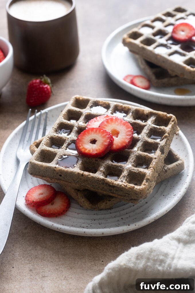 Fluffy Buckwheat Waffles with Maple & Berries 6 Stack of gluten-free buckwheat waffles on a plate with strawberry slices.