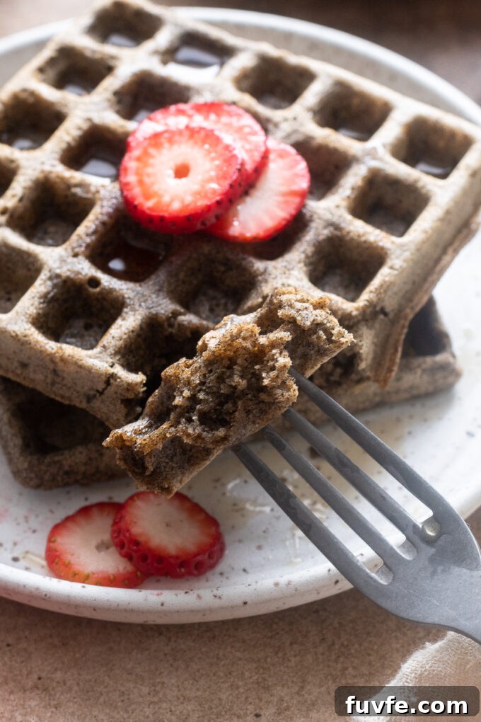 Gluten-free buckwheat waffles on a plate with fork digging in.