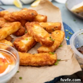 Crispy Halloumi Fries Recipe: Golden, Crunchy Cheese Fries 11 A stack of halloumi fries on brown paper and a blue marble platter with dips to the side